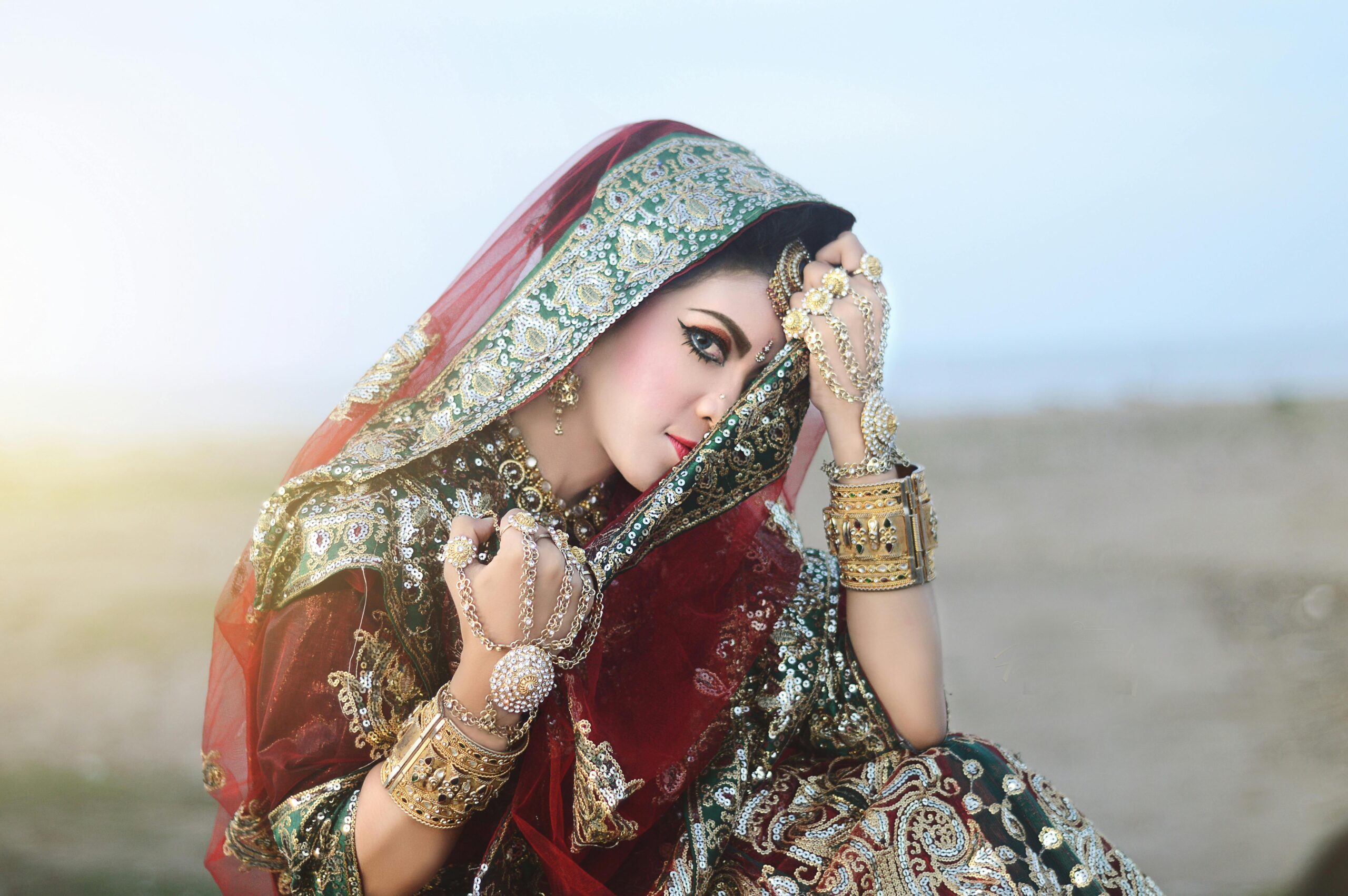 Elegant Indian woman in traditional attire posing outdoors, showcasing exquisite jewelry and fabrics.